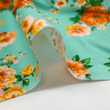 Popeline de coton imprimée bouquet orange fond vert d'eau