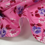 Popeline de coton imprimée roses violettes fond rose bonbon