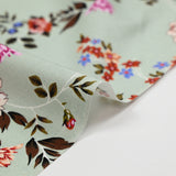 Popeline de coton imprimée fleur arabesque violet fond vert de gris