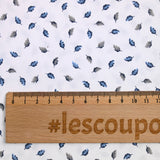 Popelín de polialgodón estampado con plumas azules y grises sobre fondo blanco.