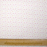 Piqué de algodón estampado con flores y corazones rosas y naranjas sobre fondo blanco