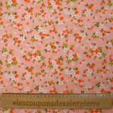 Popeline de coton imprimée composition florale fond rose pêche