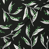 Punto de viscosa satinada estampado con una ramita de lirio de los valles, fondo negro
