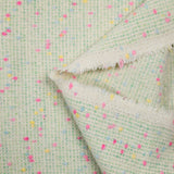 Tweed de laine mélangée confettis rose et bleu fond vert