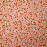 Popeline de coton imprimée composition florale fond rose pêche